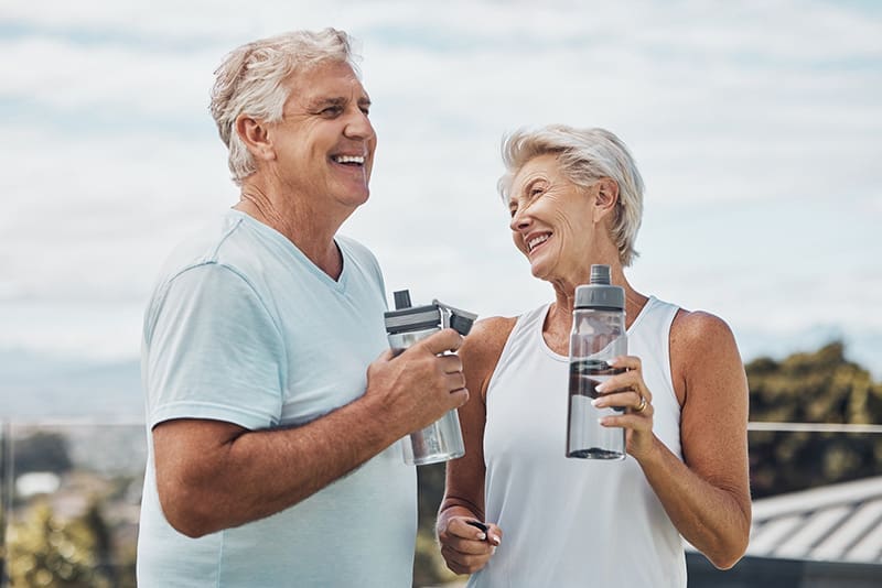 Smiling senior couple enjoying water after exercising at Charter Senior Living of Jackson in Jackson, TN