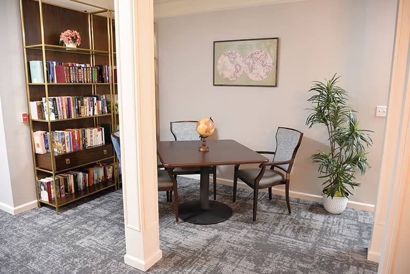 table with chairs next to bookcase full of books